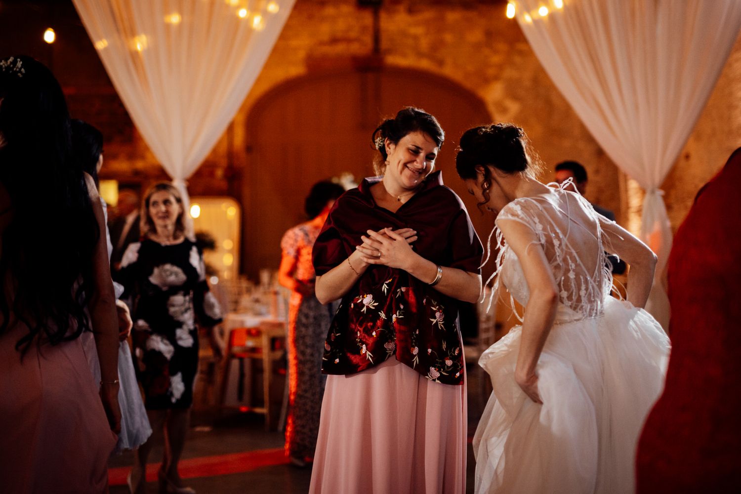 Wedding reception dance party with romantic lighting and white drape decorations.