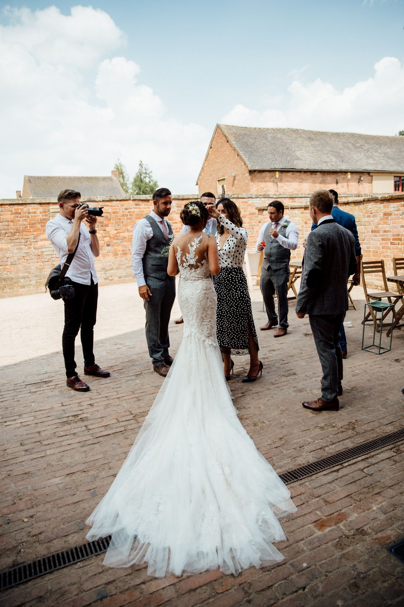 Wedding guests dancing and celebrating on outdoor brick patio near historic building.