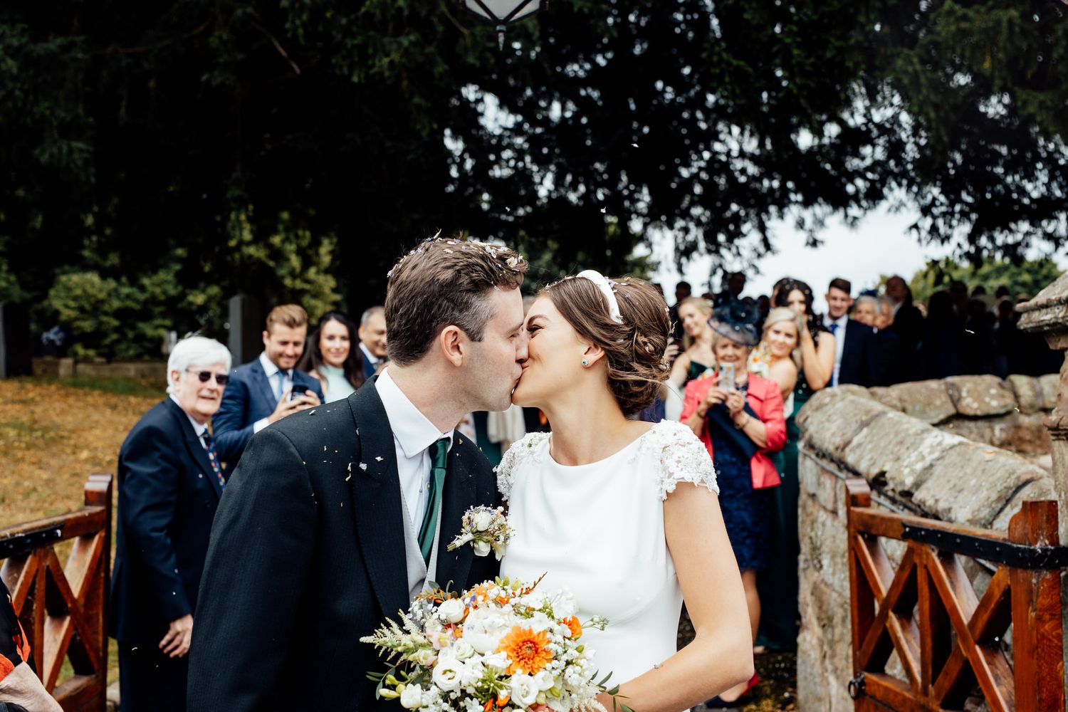 Elegant outdoor wedding ceremony with floral arrangements and wooden decor.
