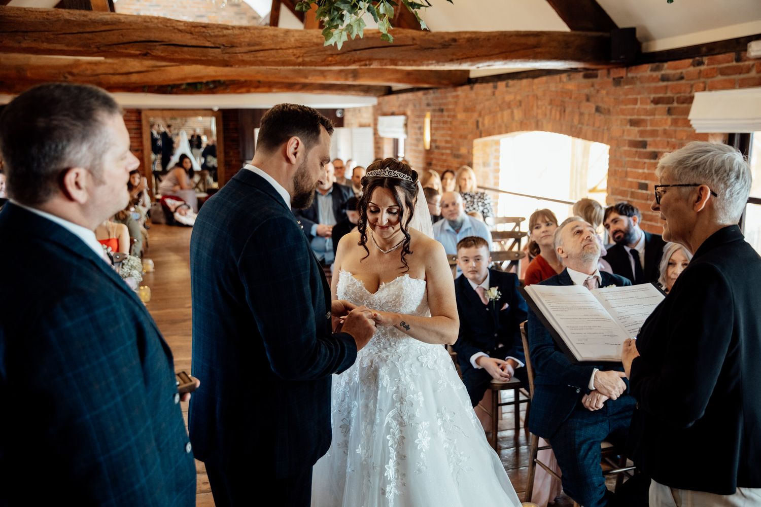 Wedding ceremony in a rustic brick-walled venue with exposed wooden beams.