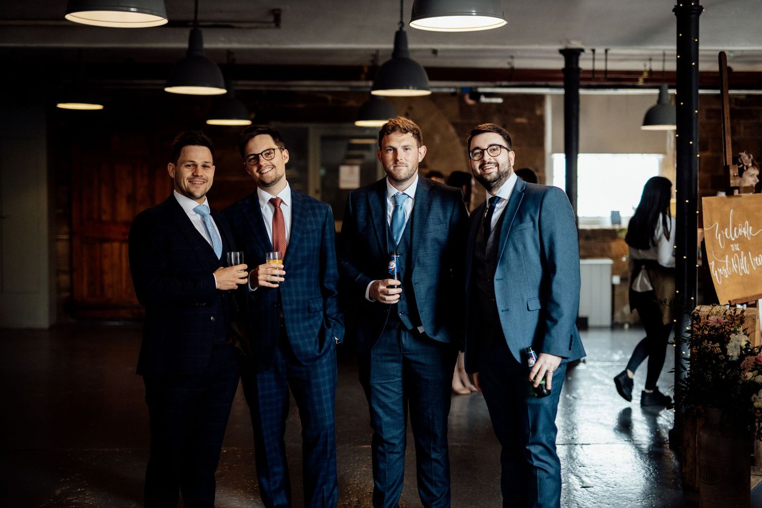 Groomsmen in navy suits gathered together in an indoor venue.