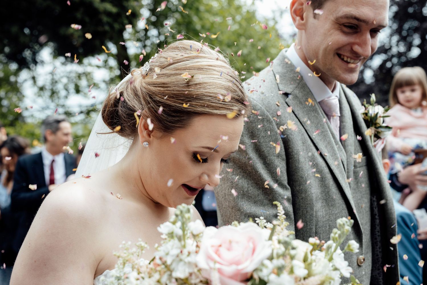 A tender moment between newlyweds with pink roses and confetti.