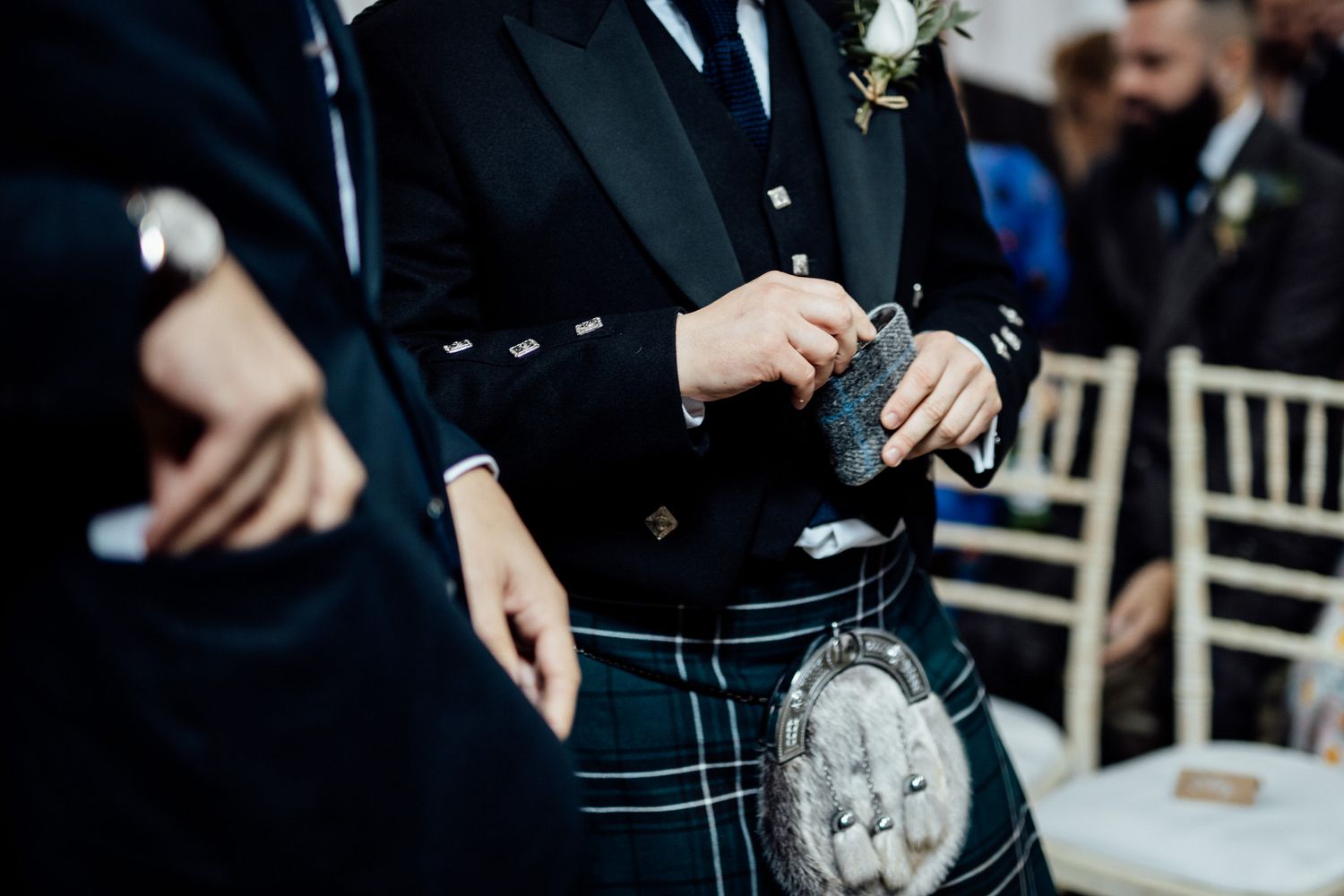 Traditional Scottish wedding attire with kilts and formal wear against industrial backdrop.