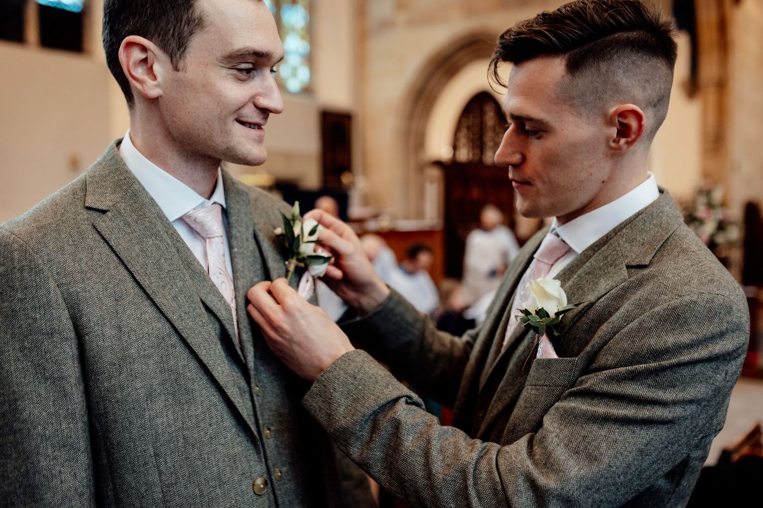 Groomsmen in grey suits sharing a candid moment before the ceremony.