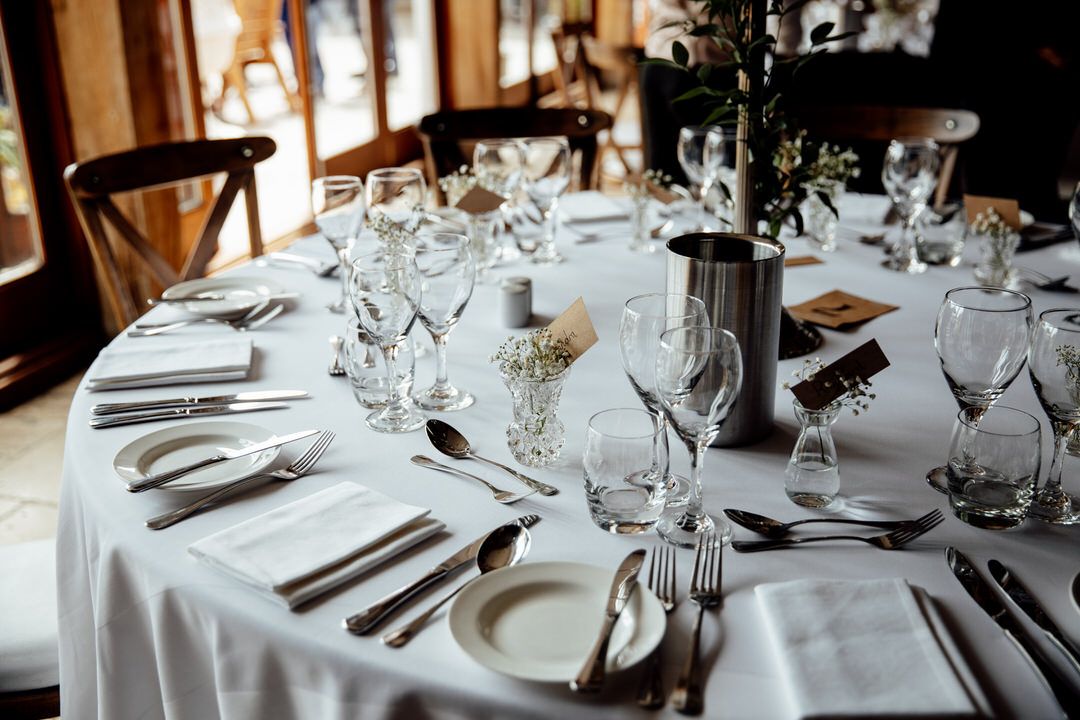 Elegant table settings with wine glasses and cutlery at a wedding reception.