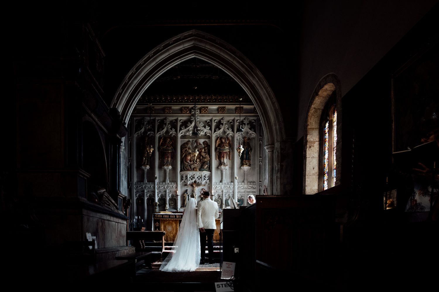 Dramatic silhouette of wedding ceremony in gothic church with arched architecture.