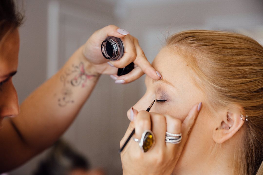 Close-up of makeup being applied to a bride's face during wedding preparations.