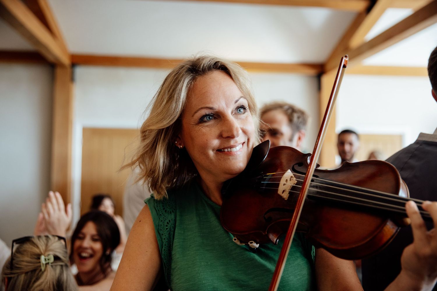 Musicians playing violins during a wedding performance in an elegant indoor space.