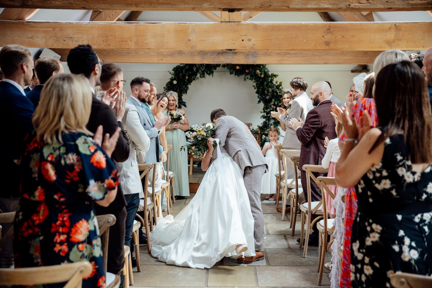 Wedding celebration inside a rustic wooden barn venue with exposed beams.