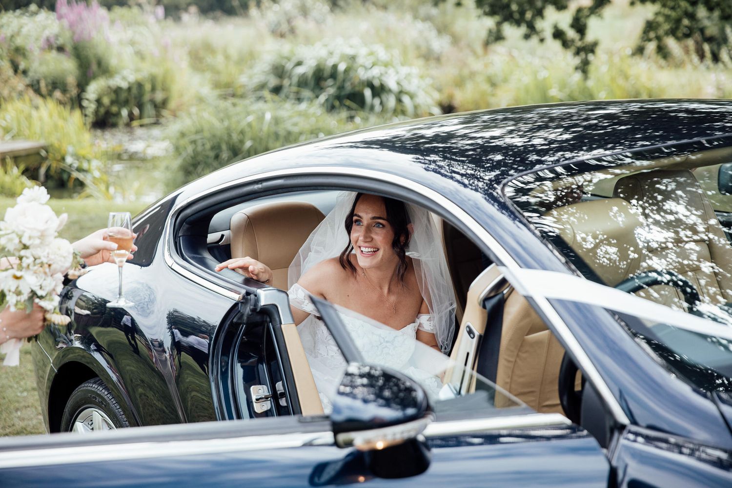 Newlyweds share a joyful moment in a luxury car after their ceremony.