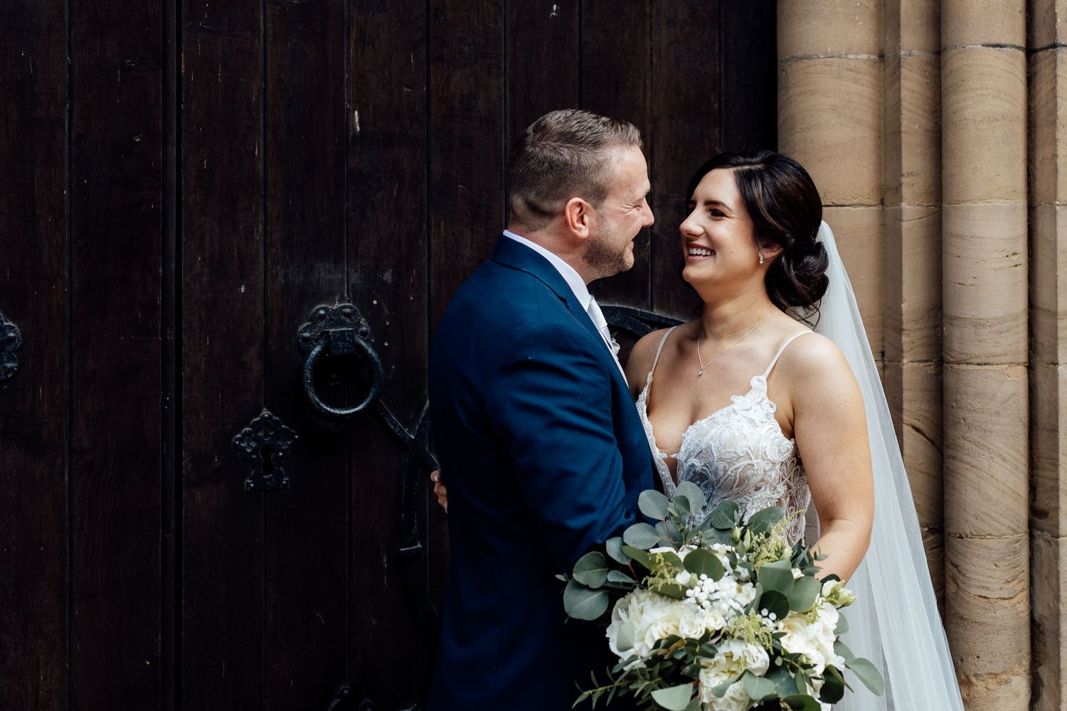Romantic wedding portrait captured between classic stone pillars.