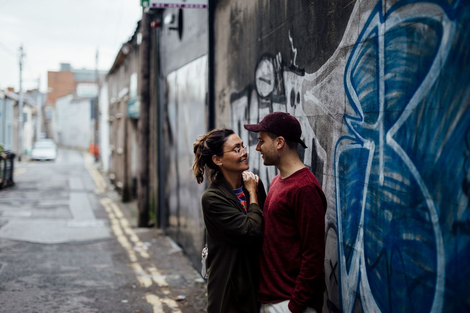 A couple shares a romantic moment against graffiti-covered walls in an urban setting.