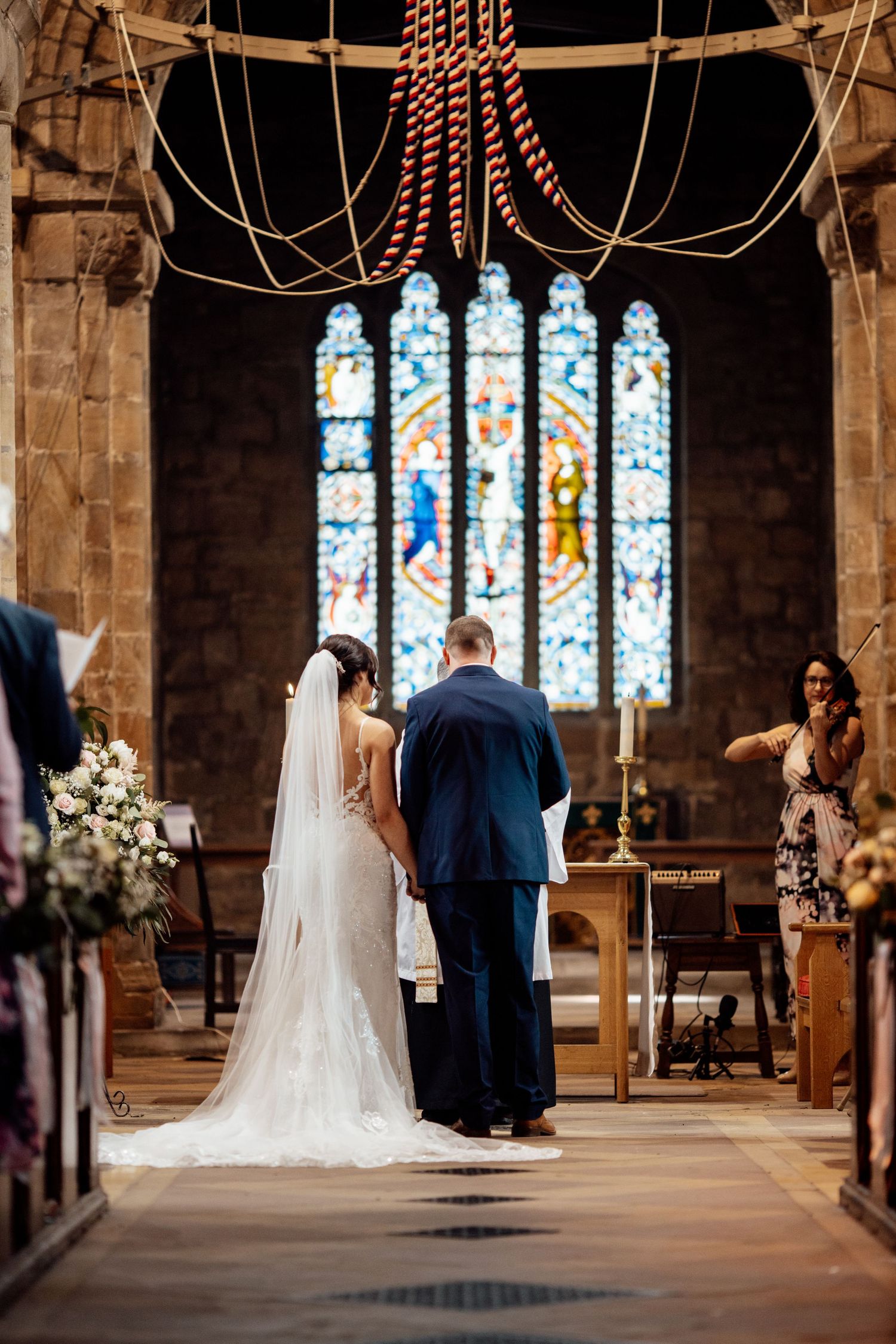 Wedding ceremony inside a historic church with beautiful stained glass windows and stone architecture.