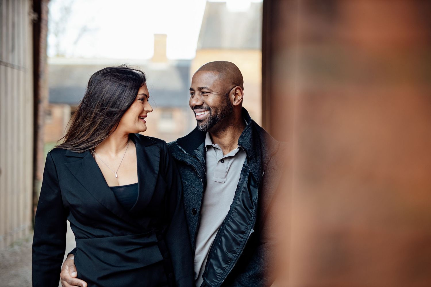 A romantic couple in formal attire shares intimate moments during an engagement photoshoot in an elegant setting.