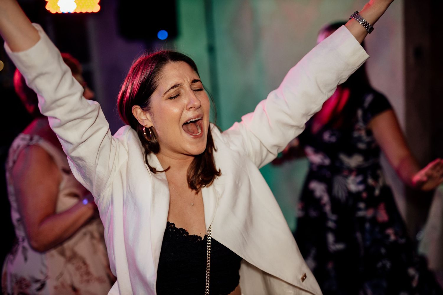 Energetic dance party scene with people celebrating under colorful lights.