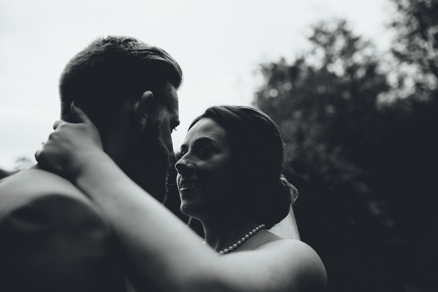 A candid black and white moment captured during a wedding celebration outdoors.
