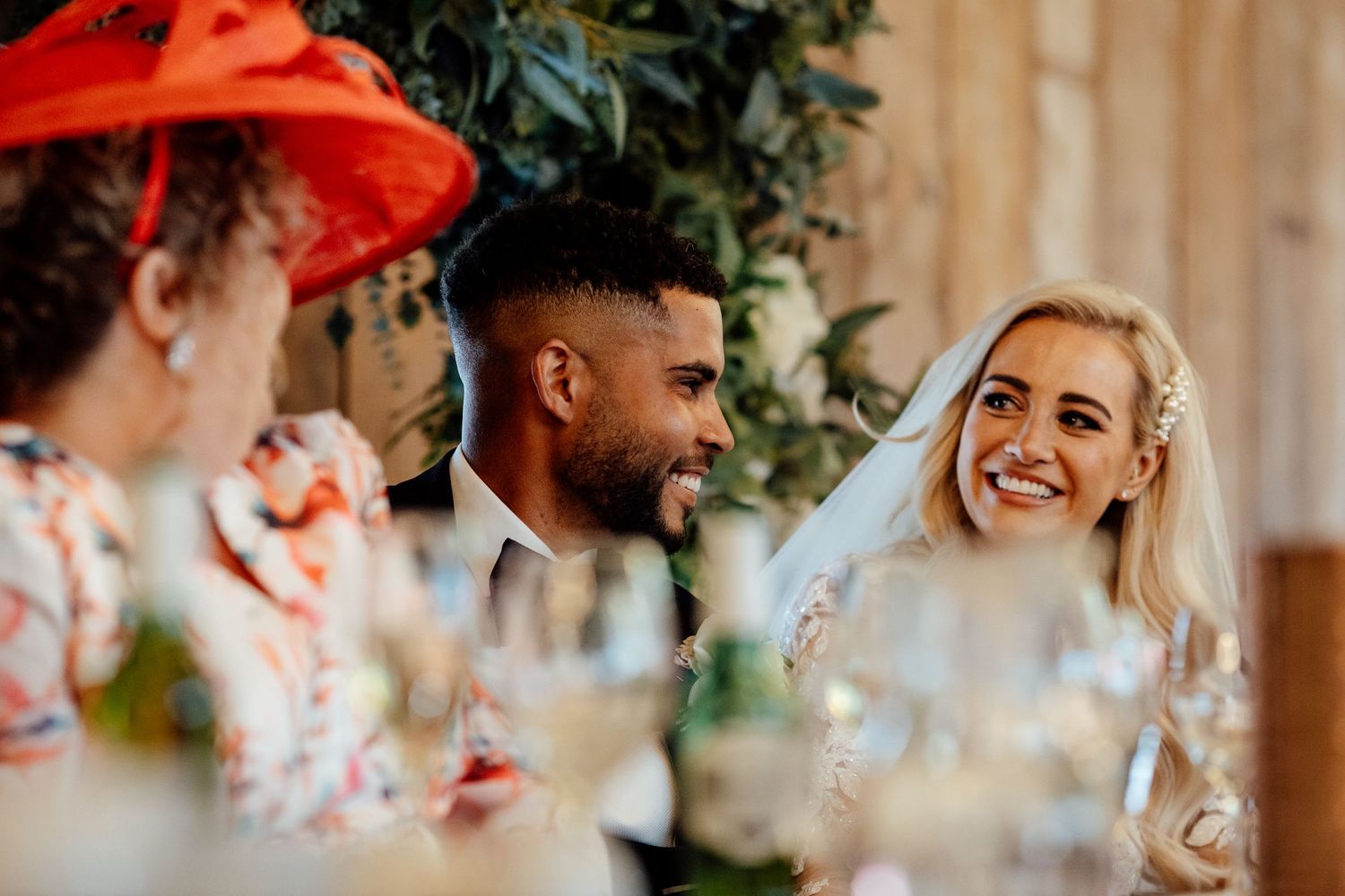 Wedding celebration with guests and decorative floral arrangements indoors.