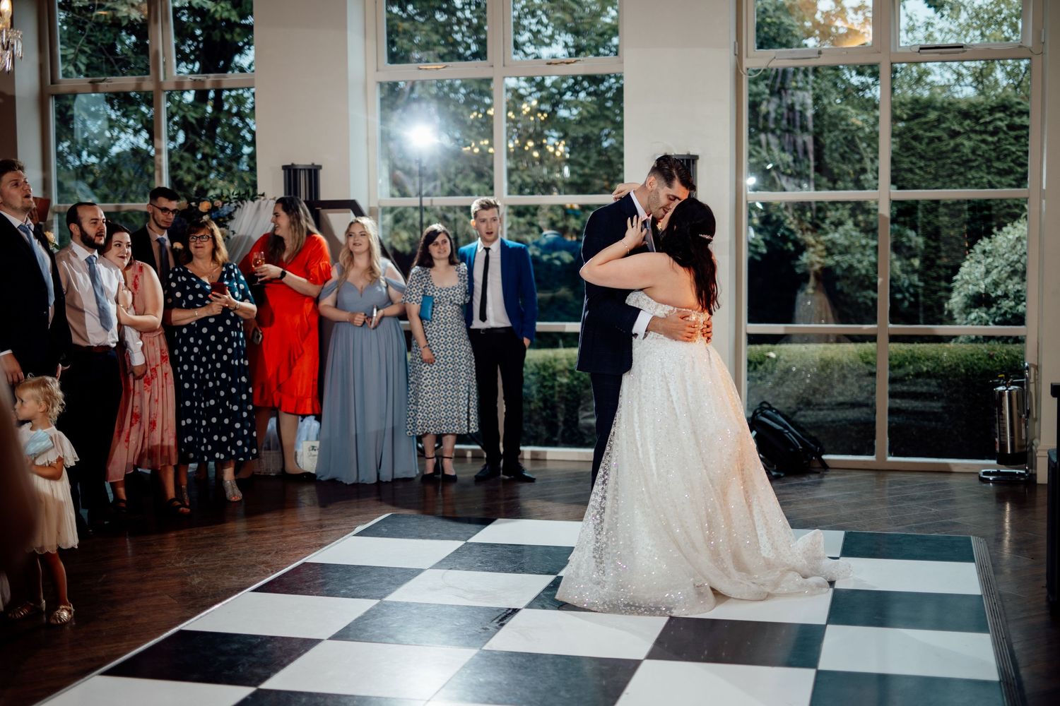 Wedding reception dance floor with black and white checkered pattern surrounded by guests.