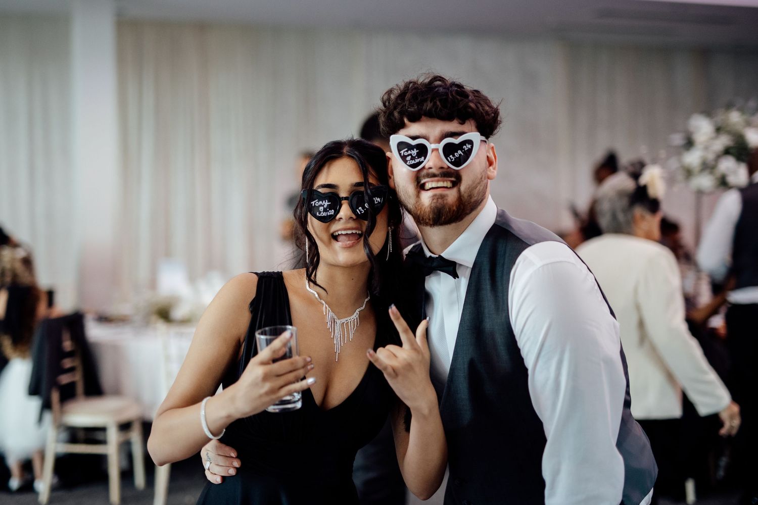 Wedding guests mingle and take photos during an indoor reception celebration.