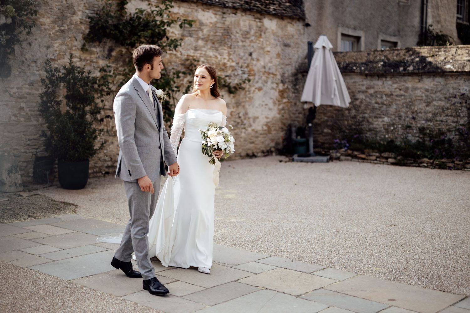 Wedding couple standing together against rustic stone wall background.