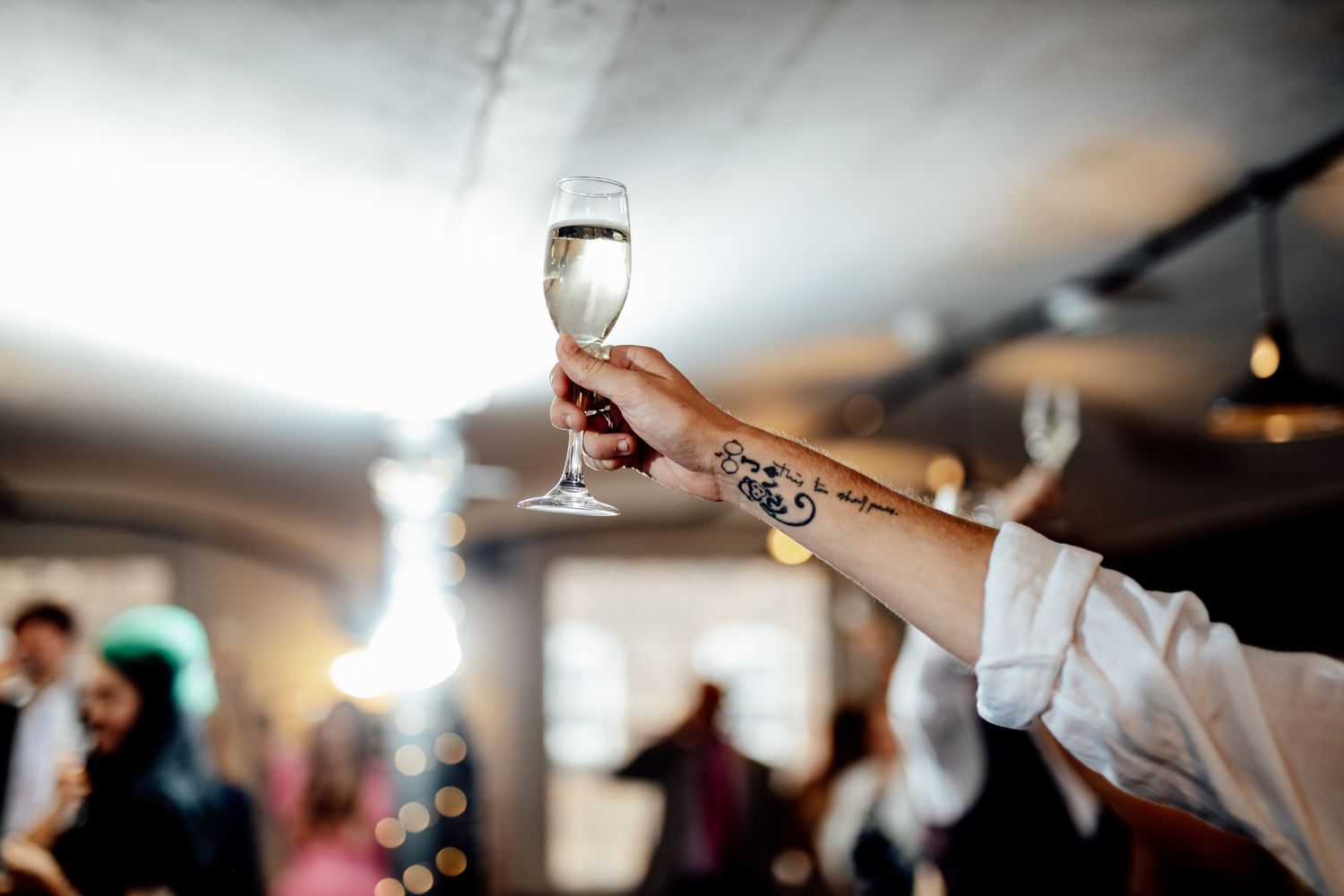 Wedding reception guests raising glasses during celebratory toast.