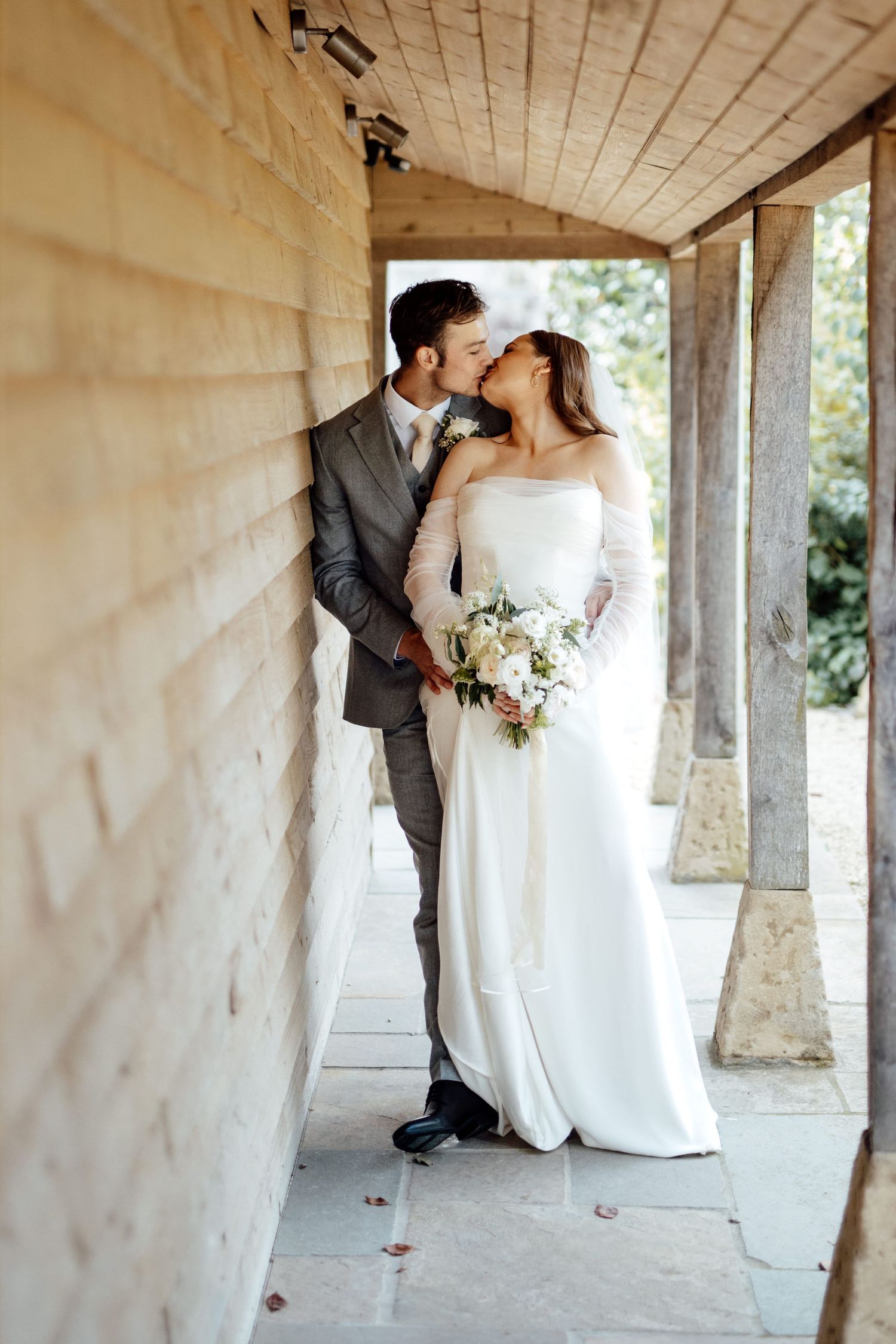 A romantic wedding portrait showing a couple embracing in a covered walkway.