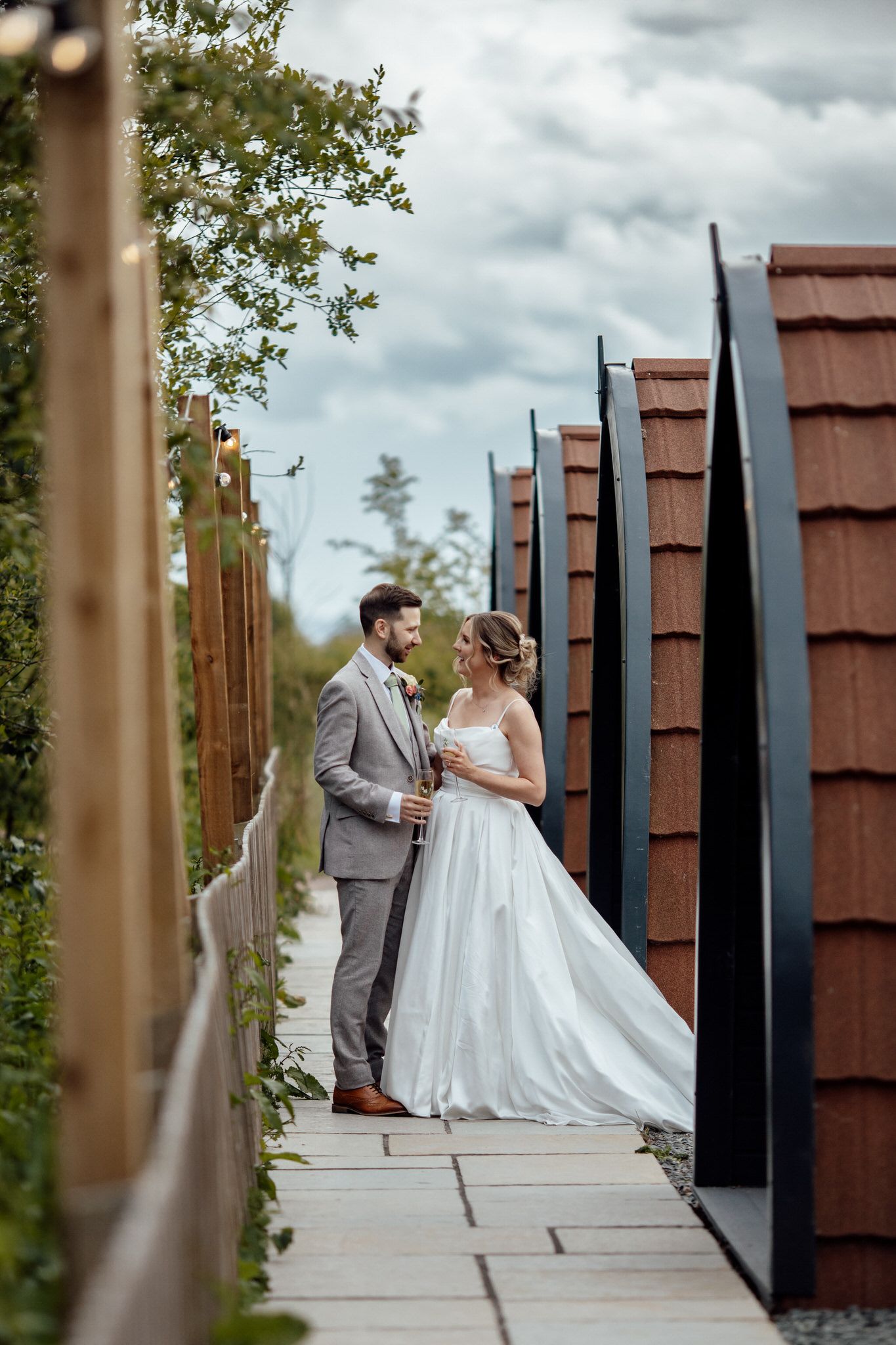 Couple shares an intimate moment on a modern architectural walkway with metal pillars.