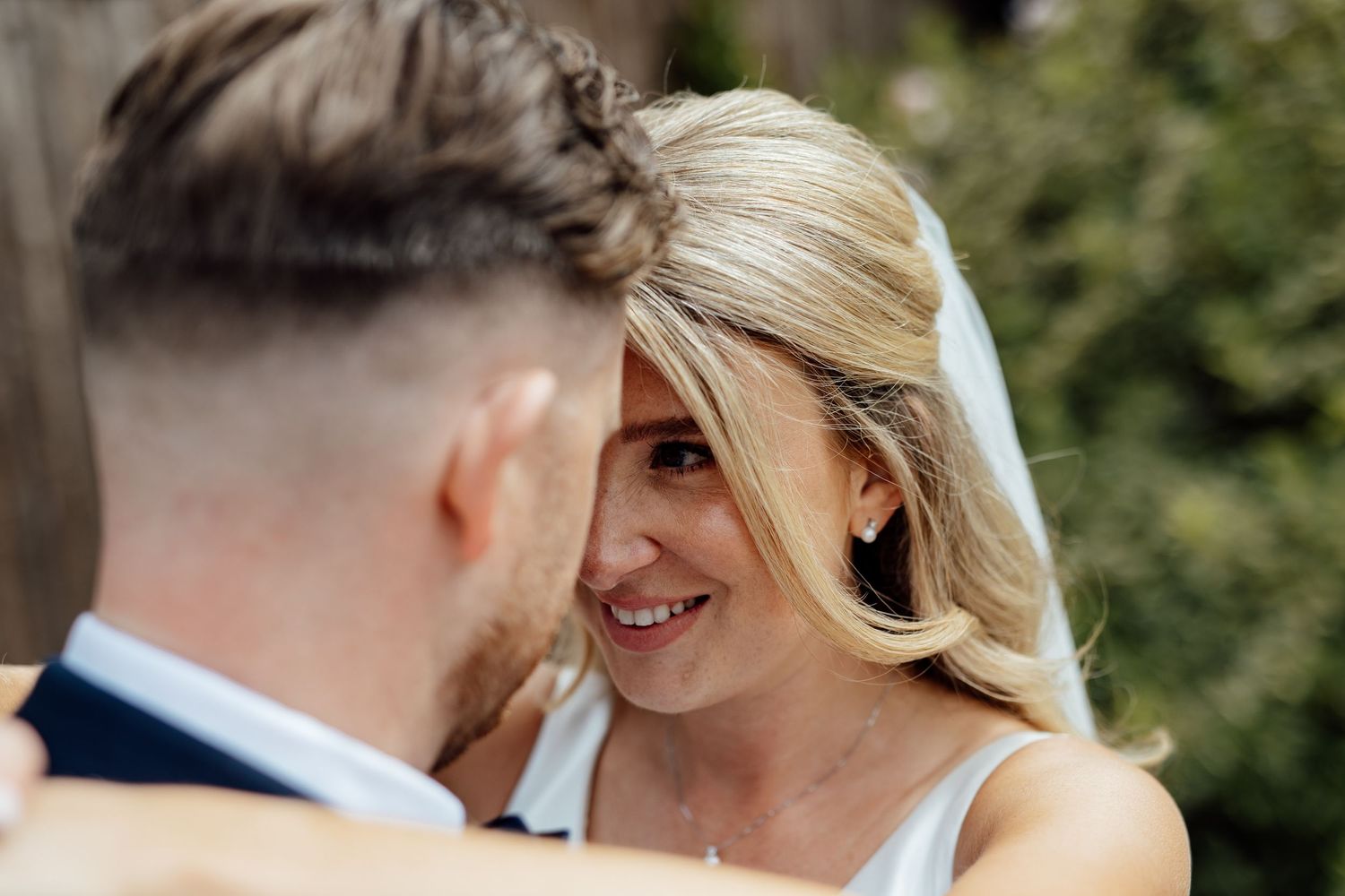 Intimate wedding moment captured in natural outdoor garden setting.