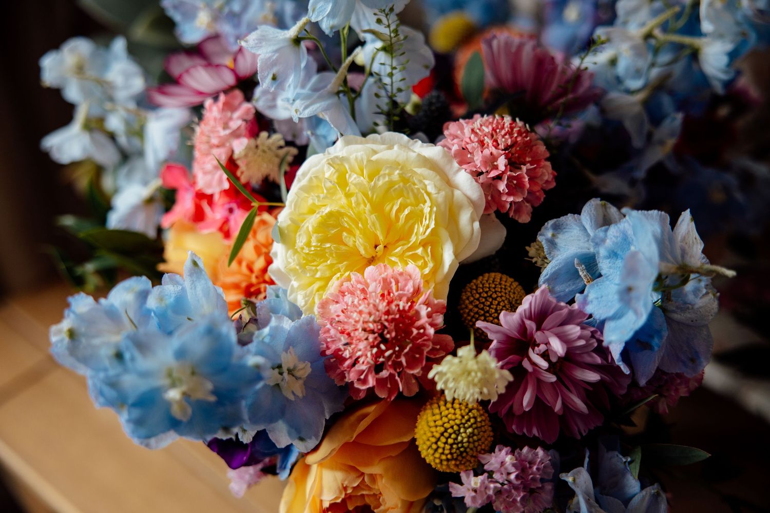 Vibrant floral arrangement with yellow roses, pink carnations, and blue hydrangeas in soft natural light.