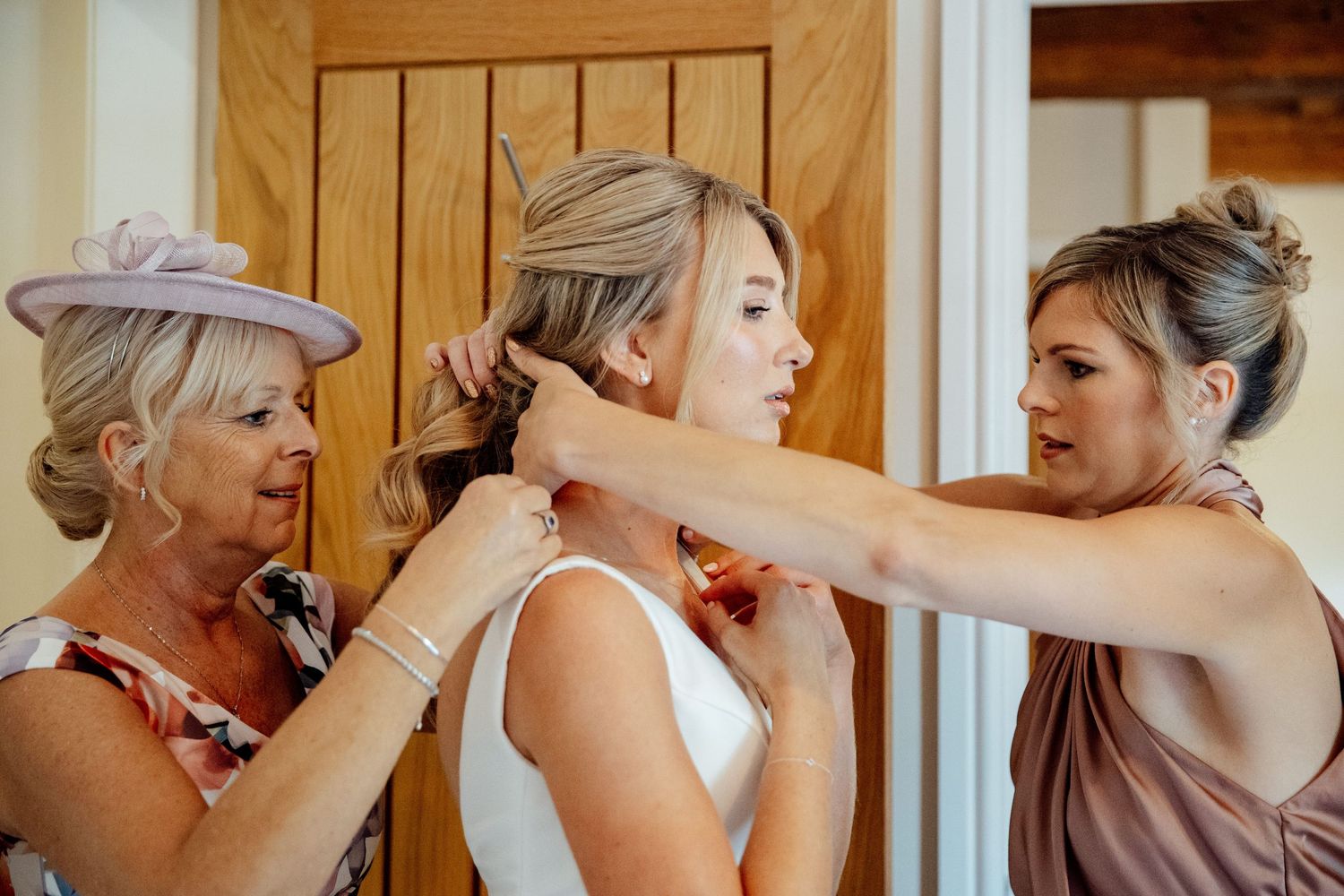 Intimate getting ready moment as final adjustments are made to wedding attire.