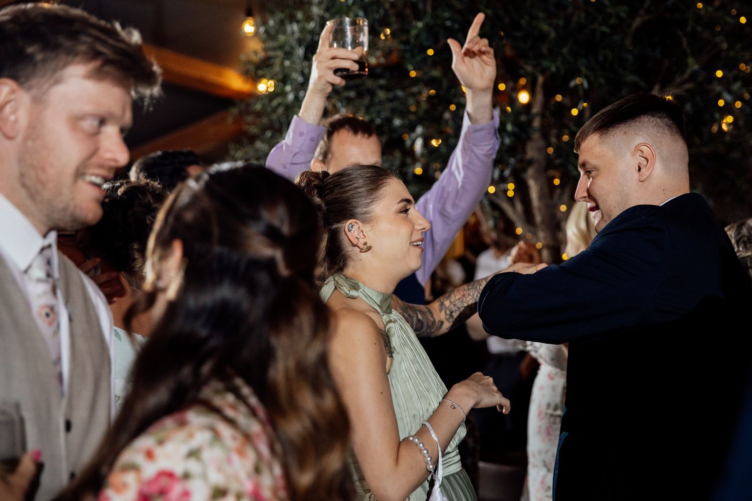 Wedding reception dance party with guests celebrating under evening lights.