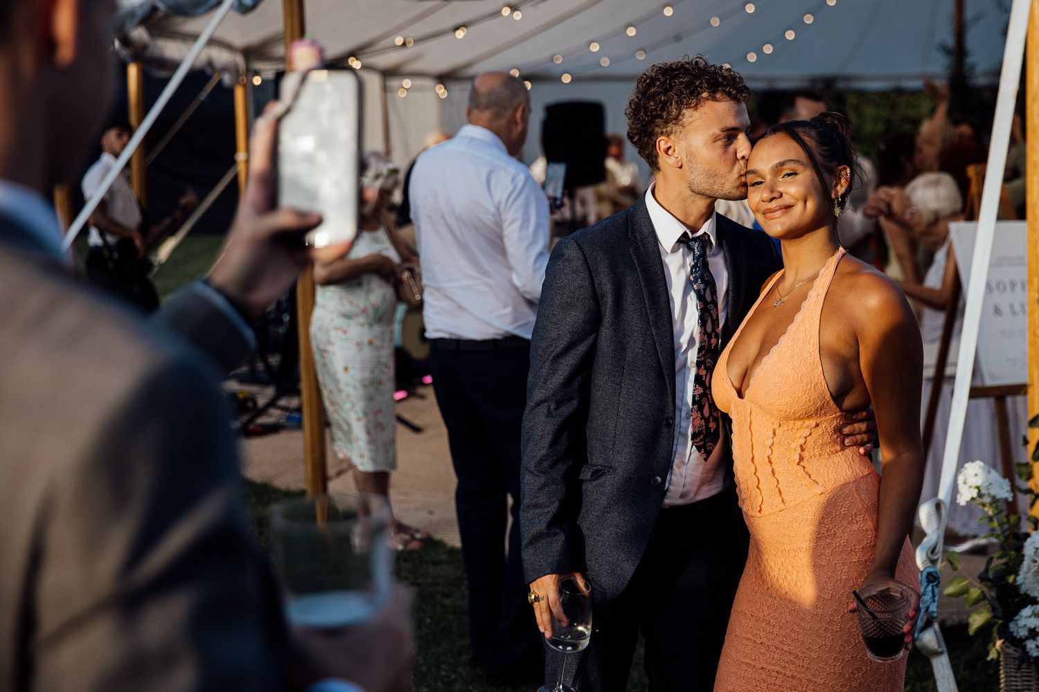 Wedding reception celebration under string lights with guests dancing and socializing.