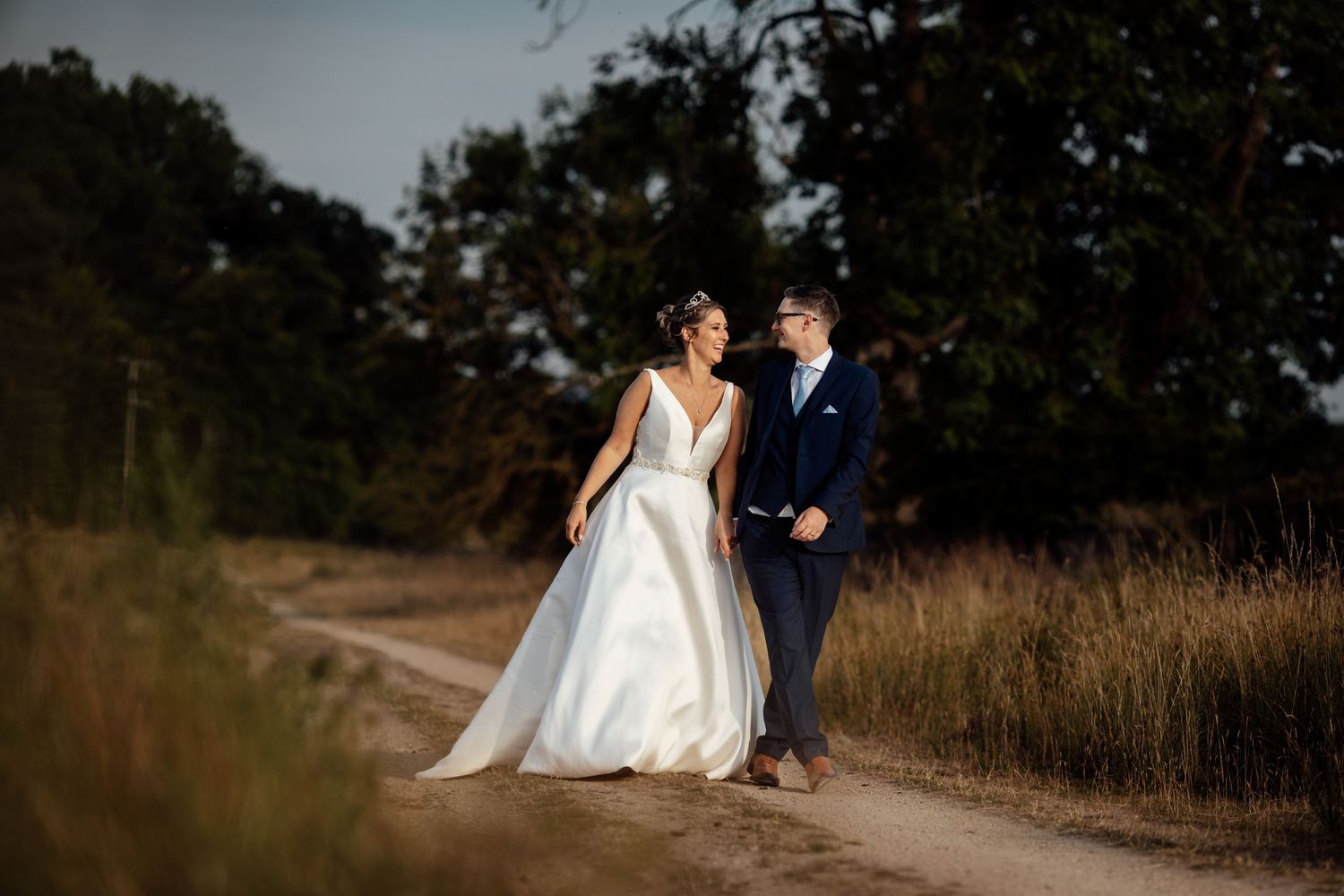 Couple shares intimate moment on rustic dirt path during sunset photo session.