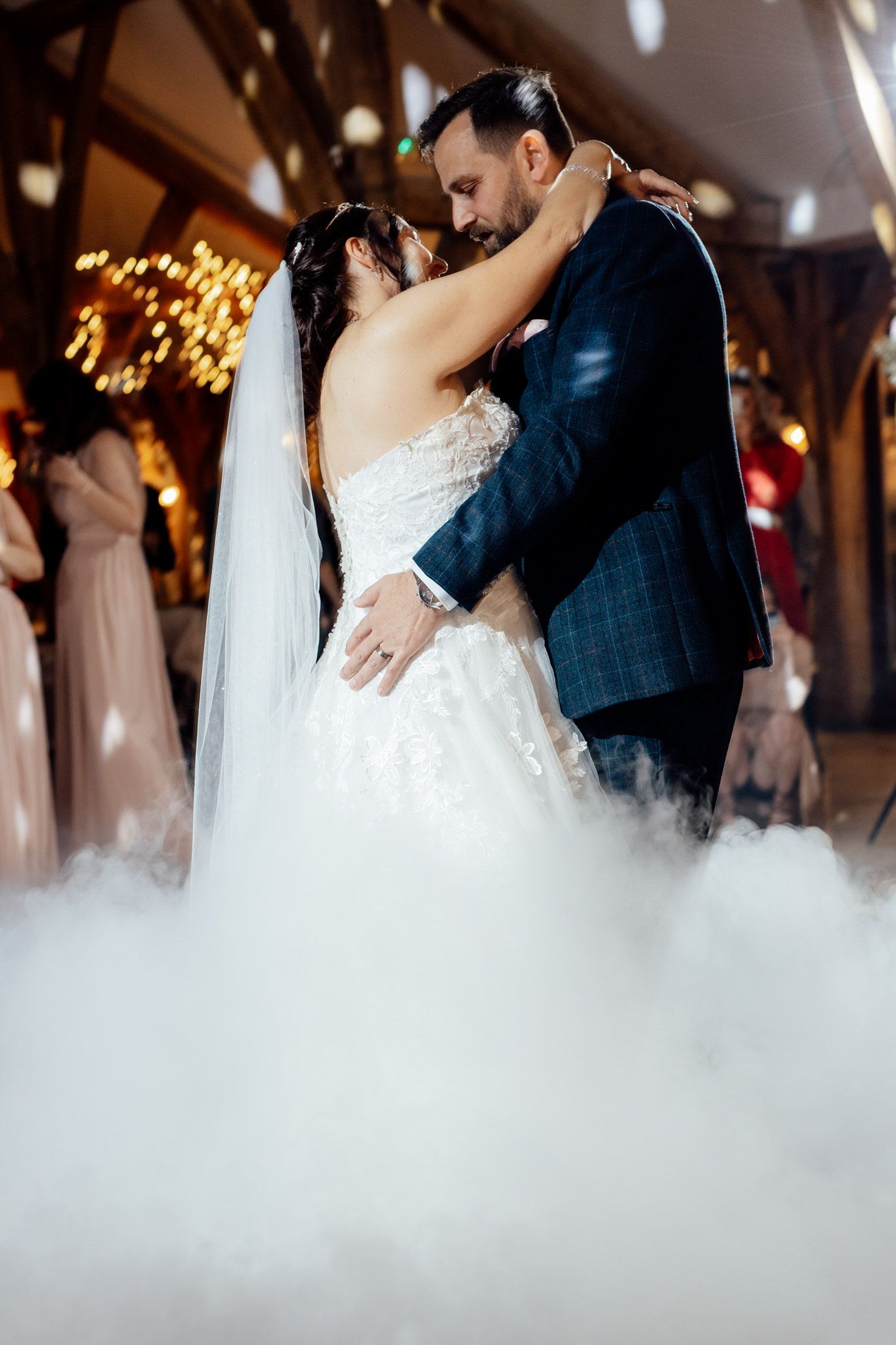 Couple dances surrounded by atmospheric fog effect on reception dance floor.