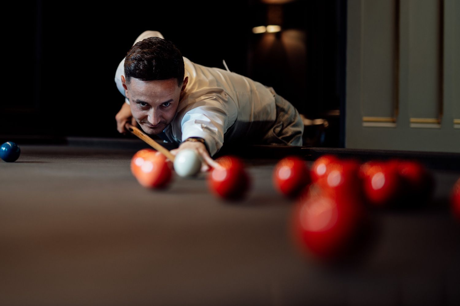 Atmospheric shot of people playing pool in dim lighting.