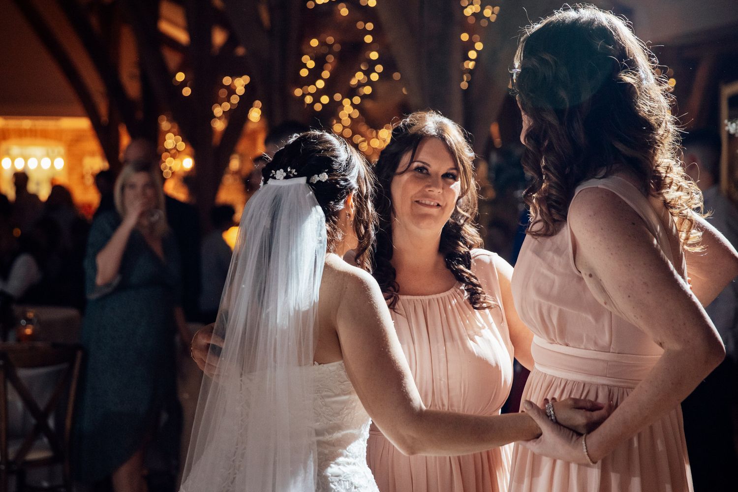 Wedding guests chat during an evening reception with warm string lights in the background.