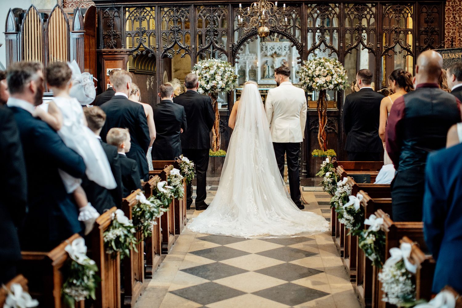 An elegant church wedding ceremony with floral decorations along the aisle.