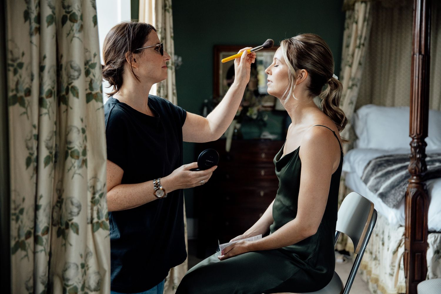 Wedding preparation moments captured in a room with floral curtains.