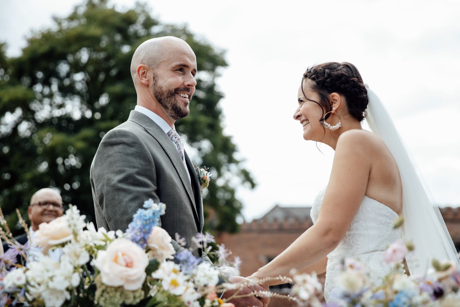 Wedding couple sharing a joyful moment among floral arrangements outdoors.