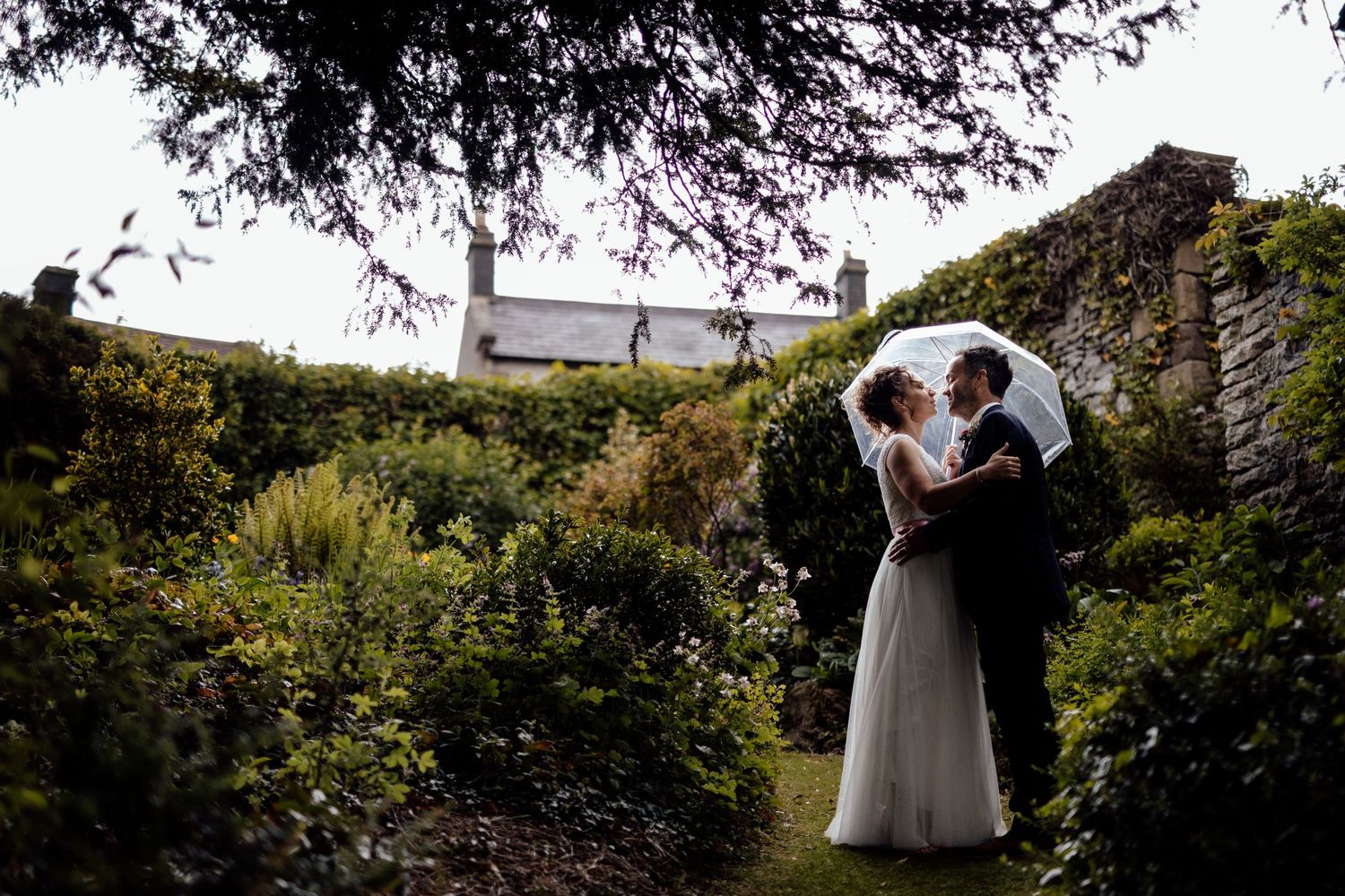 Silhouettes of wedding couple against natural outdoor scenery with trees.