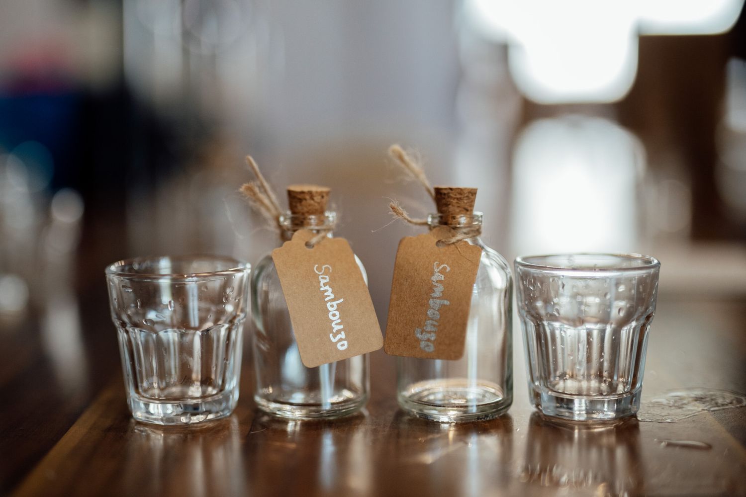 Empty drinking glasses lined up on wooden table at wedding reception.