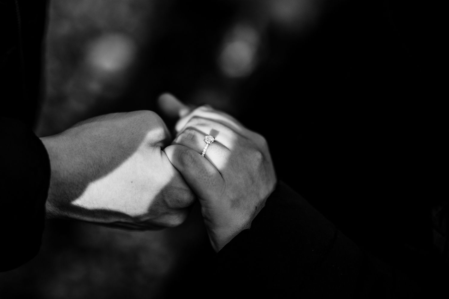 Artistic black and white close-up of hands with romantic lighting.