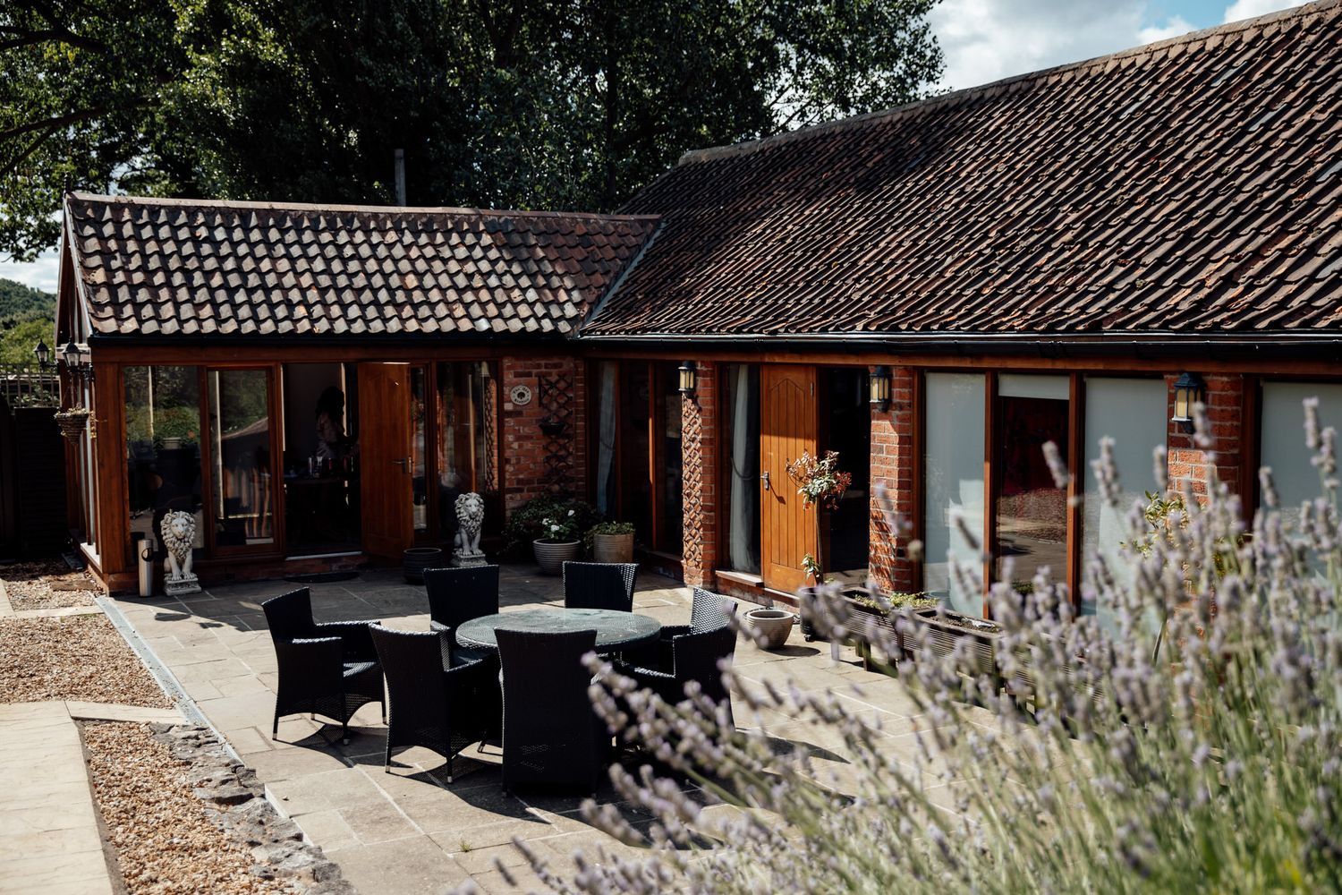 Exterior view of rustic brick buildings with tiled roofs and landscaping.