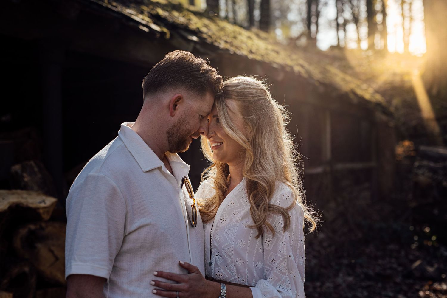 Intimate couple's portrait with golden sunlight filtering through trees.
