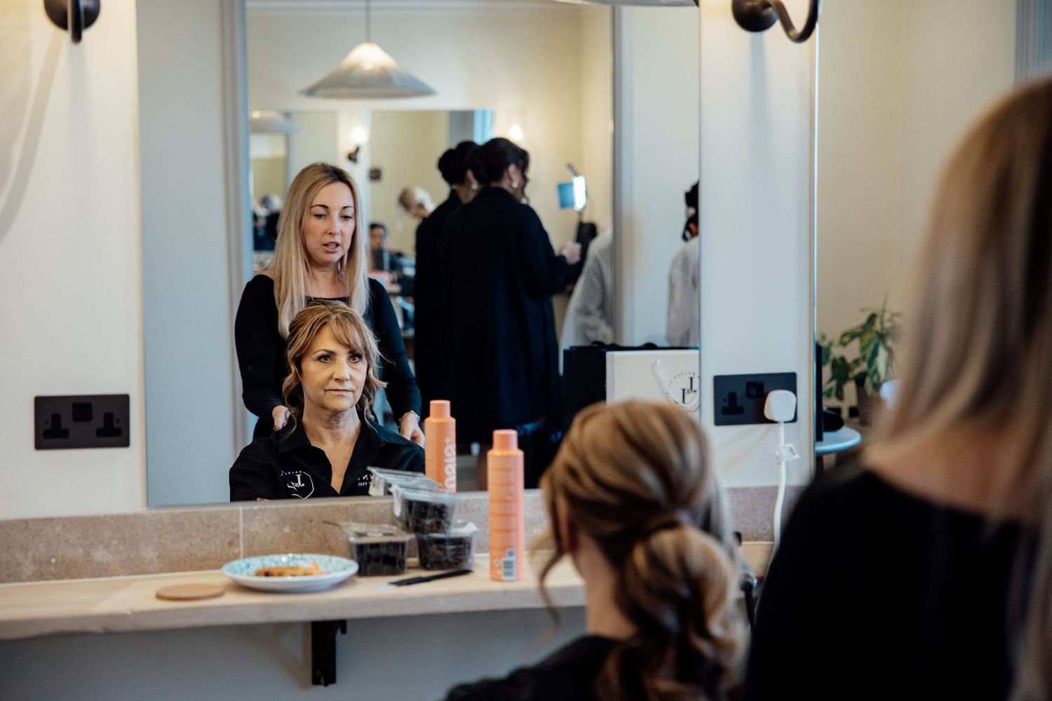 Professional makeup artist applying cosmetics to client in bright modern salon setting.