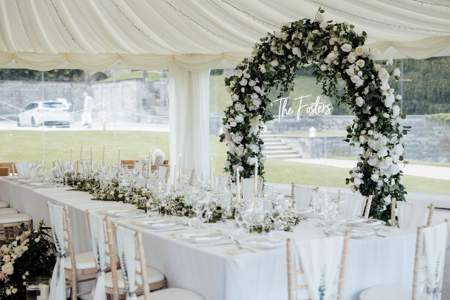 Elegant wedding reception setup with white draped tent and floral centerpieces.