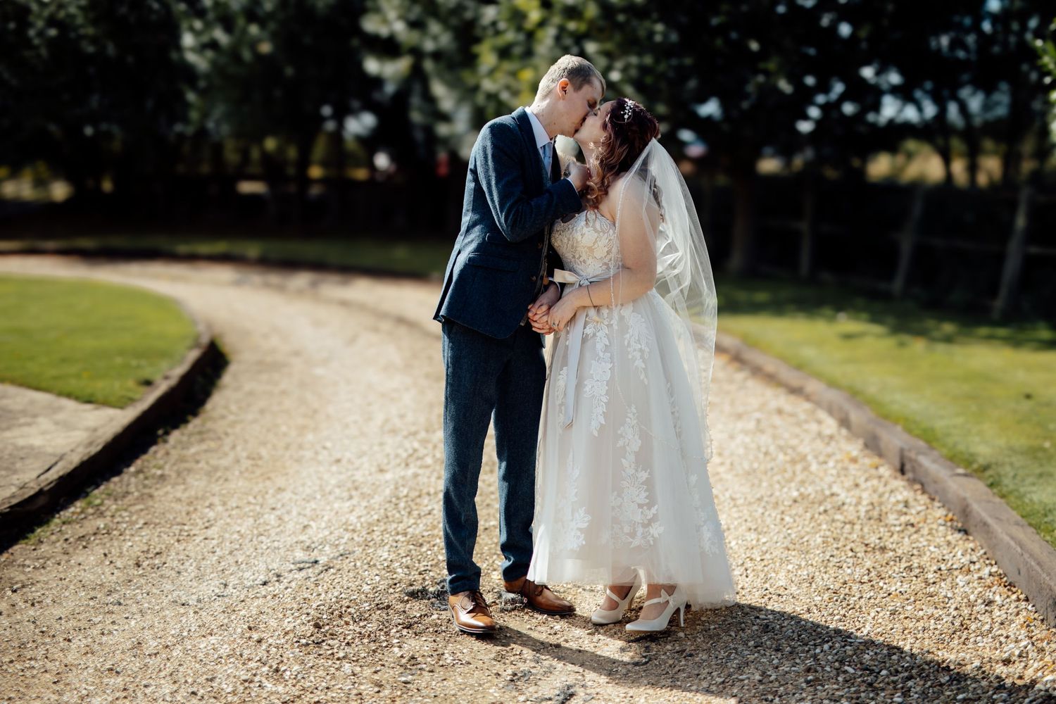 Wedding couple walking along a gravel path surrounded by lush greenery on their special day.