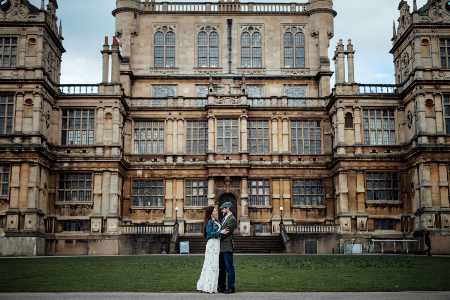 A couple poses in front of a grand historic building with ornate architecture.