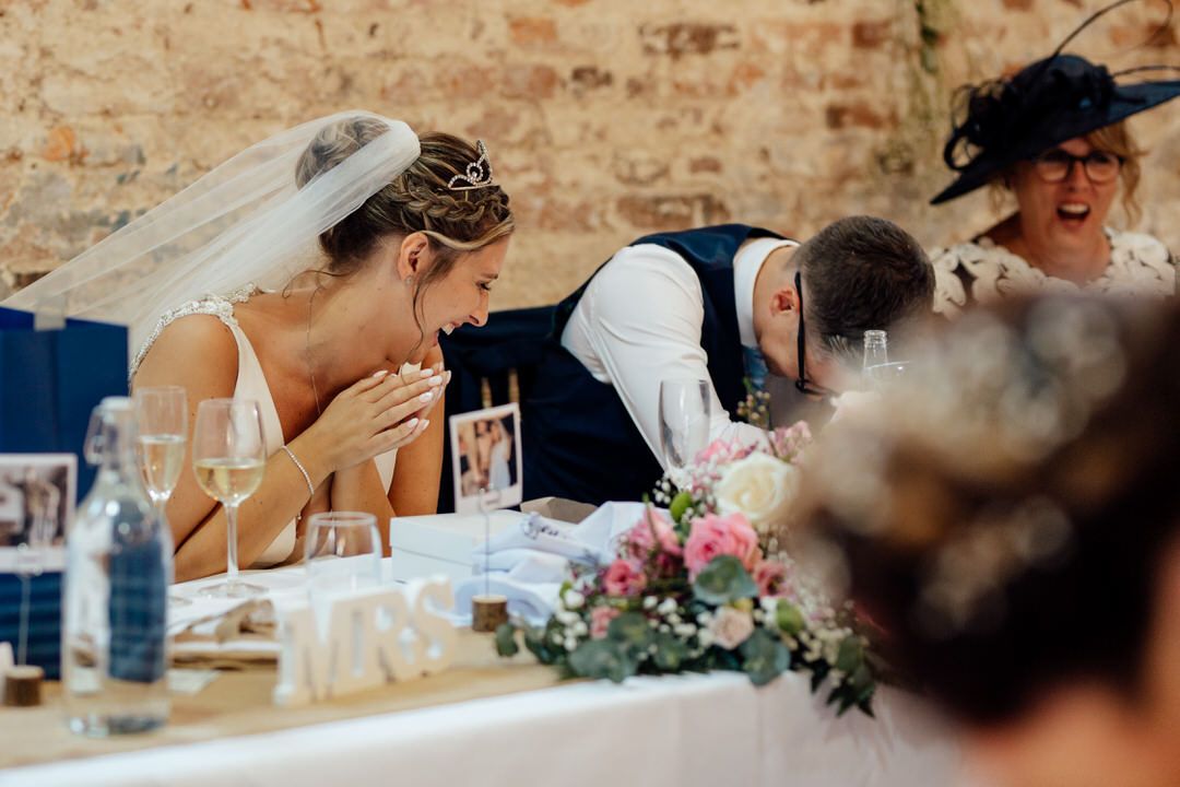 Emotional reactions during wedding reception speeches at decorated head table with floral centerpieces.