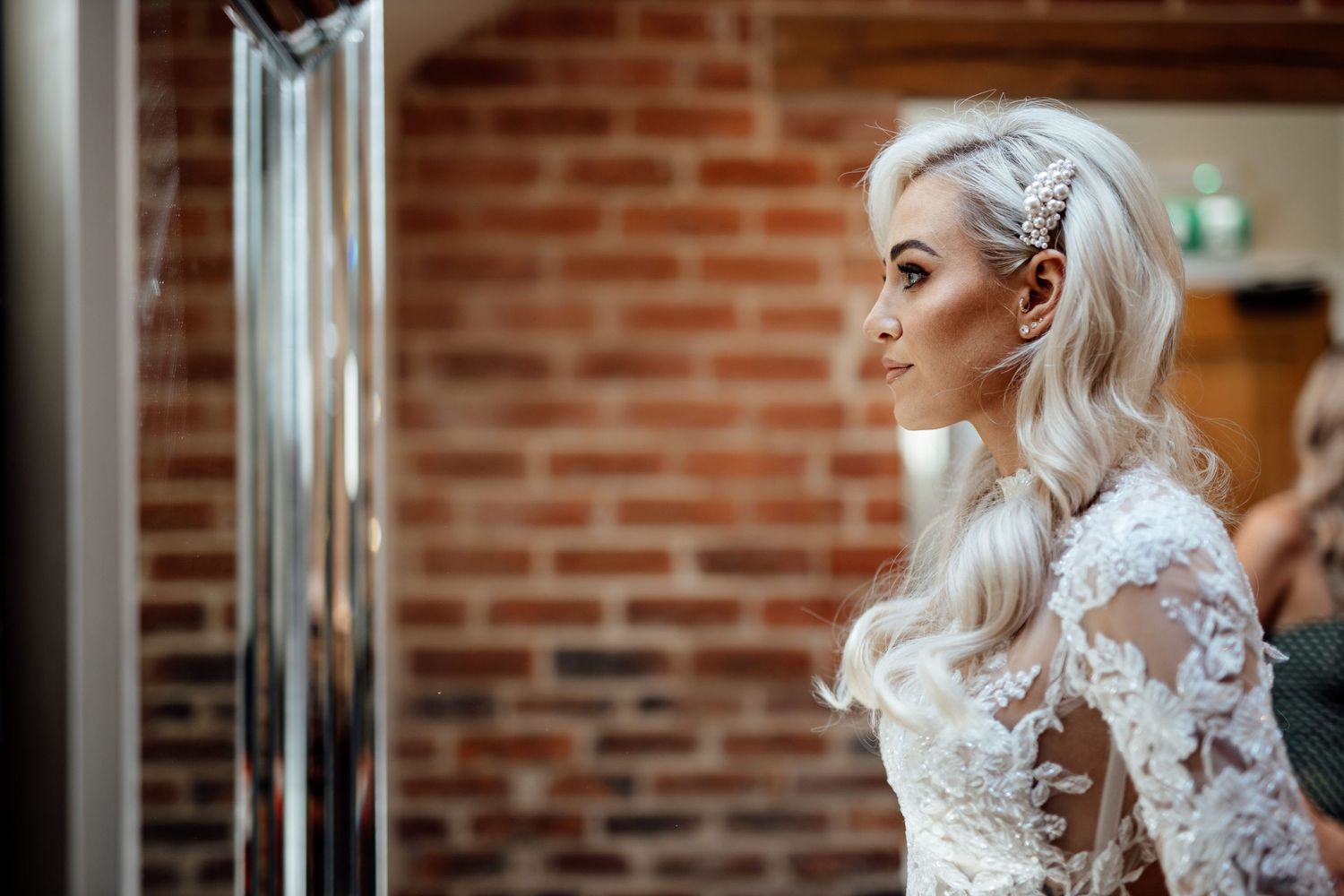 Elegant lace wedding dress details against brick wall background.